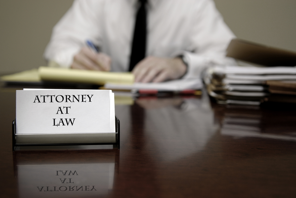 Immigration attorney writing at desk with attorney at law sign