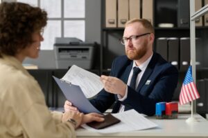 Male immigration attorney sitting at desk reviewing paperwork with client