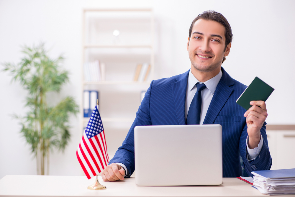 Immigration attorney smiling at desk with computer and american flag