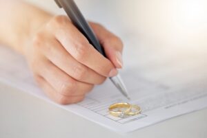 Female signing marriage visa papers with wedding rings