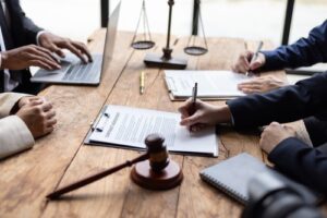Lawyers and clients signing contract documents across office table during meeting