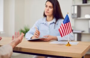 woman holding notepad across desk with small US flag during office meeting