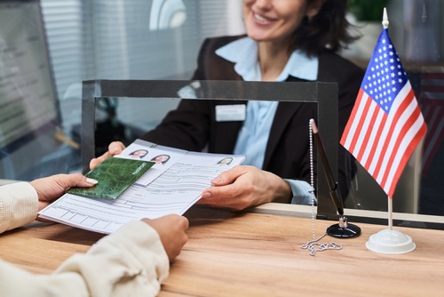 immigration officer reviewing passport and visa application documents at US government desk